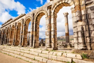 Ancient Roman ruins at Volubilis in Morocco under a clear blue sky, showcasing rich Morocco history."