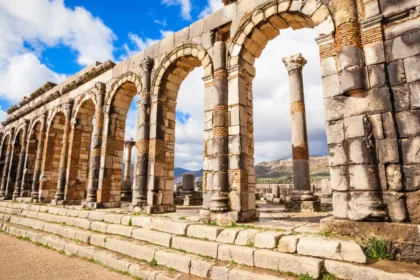 Ancient Roman ruins at Volubilis in Morocco under a clear blue sky, showcasing rich Morocco history."