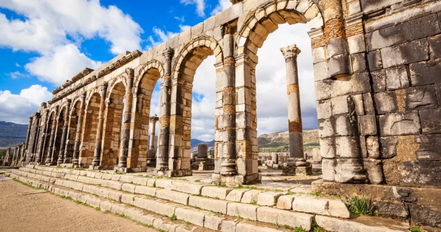 Ancient Roman ruins at Volubilis in Morocco under a clear blue sky, showcasing rich Morocco history."