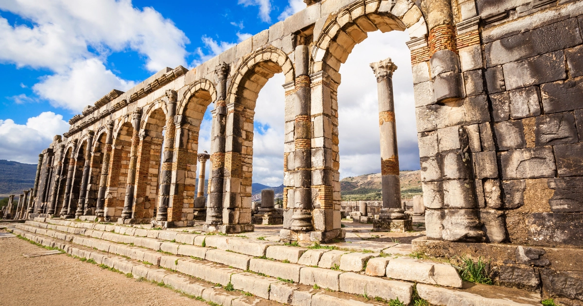 Ancient Roman ruins at Volubilis in Morocco under a clear blue sky, showcasing rich Morocco history."